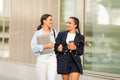 Two cheerful young ladies walking by street, chatting Royalty Free Stock Photo