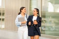 Two cheerful young ladies walking by street, chatting