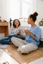 Two young girls talking and drinking coffee while sitting on floor at home Royalty Free Stock Photo