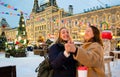 Two cheerful young women with cardboard cups with hot drinks dance and laugh. Christmas Fair in Moscow on Red Square Royalty Free Stock Photo
