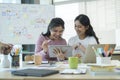 Two cheerful young women are sharing information, working on project together at creative office Royalty Free Stock Photo