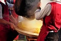 Two chef pour the just made and still steaming Polenta onto the round wooden cutting board