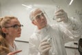 Two chemist colleagues write formulas on glass. Caucasian elderly man and young woman brainstorming. Royalty Free Stock Photo