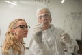 Two chemist colleagues write formulas on glass. Caucasian elderly man and young woman brainstorming. Royalty Free Stock Photo