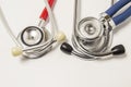 Two chestpieces of stethoscopes large diaphragm down with red and blue acoustic tubes lie on white background. Concept for cardiol