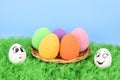 Two chicken eggs with painted faces. Between them there is a wicker dish with Royalty Free Stock Photo