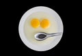 Two chicken Raw egg yolks and stainless spoon in white dish Royalty Free Stock Photo