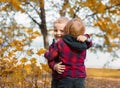 Two child boys in identical red shirts in a cage are hugging in an autumn park Royalty Free Stock Photo