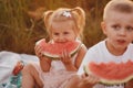 two child are eating watermelon in the garden. Kids eat fruit outdoors. Healthy snack for children. Little girl and boy Royalty Free Stock Photo