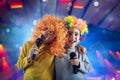 Two child sing a song with microphone and funny wig