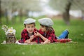 Two children, boy brothers, reading a book and eating strawberries in the park Royalty Free Stock Photo