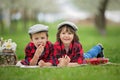 Two children, boy brothers, reading a book and eating strawberries in the park Royalty Free Stock Photo