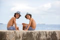 Two children, boy brothers, sitting on a concrete wall on pier on the sea, contemplating the boats Royalty Free Stock Photo