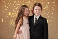 Two children boy and girl are in christmas lights, yellow background, winter holiday concept Royalty Free Stock Photo