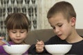 Two children boy and girl eating soup with spoon from a plate wi Royalty Free Stock Photo