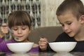 Two children boy and girl eating soup with spoon from a plate wi Royalty Free Stock Photo