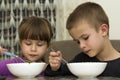 Two children boy and girl eating soup with spoon from a plate wi Royalty Free Stock Photo