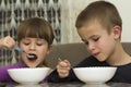 Two children boy and girl eating soup with spoon from a plate wi Royalty Free Stock Photo