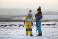 Two children boy and girl having fun outside in winter playing with photo camera on a tripod on snow covered field Royalty Free Stock Photo