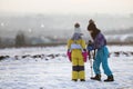 Two children boy and girl having fun outside in winter playing with photo camera on a tripod on snow covered field Royalty Free Stock Photo