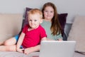 Two children a boy and a girl lie on a sofa in home clothes and watch videos on a laptop and look at camera for a moment Royalty Free Stock Photo