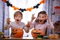 Two children, a boy and a girl, are sitting at a table near Halloween pumpkins and make scary faces asking for treats Royalty Free Stock Photo