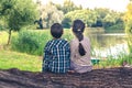 Two children, boy and girl, sitting on trunk of tree and watching at lake scenery Royalty Free Stock Photo