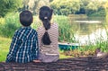 Two children, boy and girl, sitting on trunk of tree and watching at lake scenery Royalty Free Stock Photo