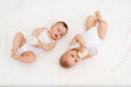 Two children a boy and a girl-twins of 8 months drink milk from a bottle on the bed in the nursery, feeding the baby, baby food Royalty Free Stock Photo