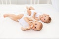 Two children a boy and a girl-twins of 8 months drink milk from a bottle on the bed in the nursery, feeding the baby, baby food Royalty Free Stock Photo