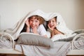 Two children, brother and sister, squirmy on the bed in the bedroom.