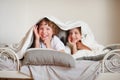 Two children, brother and sister, squirmy on the bed in the bedroom.