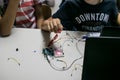 two children build a prototype circuit with a red laser controlled by a microcontroller. STEAM and coding activity