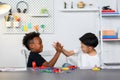 Two Children of different ethnicities high-fived each other after completing a collaborative project on electrical circuits.