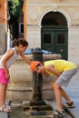 Two children drink water from a fountain on the island of Venice