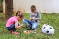 Brother and sister playing on ground and eats sweets candy from pinata toy. Boy and girl on meadow in garden playing Royalty Free Stock Photo