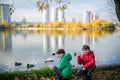 Two children feed the wild ducks and shoal of small fish in azur