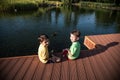 Two children feed the wild ducks and shoal of small fish in azure clean transparent lake. Brother boys are best friends. Summer Royalty Free Stock Photo