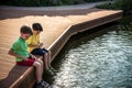 Two children feed the wild ducks and shoal of small fish in azure clean transparent lake. Brother boys are best friends. Summer Royalty Free Stock Photo