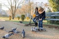 Two children girls feed birds pigeons on sunny autumn day