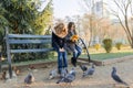 Two children girls feed birds pigeons on sunny autumn day