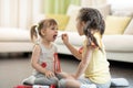 Two kids girls playing doctor at home. Toddler girl opens her mouth and says aaah. Child girl examining little sister.