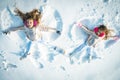 Two children girls on a snow angel wings shows. Funny kids playing and making a snow angel in the snow. Top view. Royalty Free Stock Photo