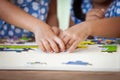 Two children hands helping and trying to connect jigsaw puzzle