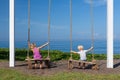 Two children have fun swinging on rope swing at beach Royalty Free Stock Photo