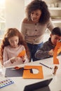 Two Children At Home With Mother Having Fun Making Craft Together