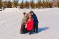 two children hug smiling mother in the snow in the winter. Happy family. people in outer clothing Royalty Free Stock Photo