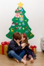 Two children kissing in the floor in front of a Christmas tree Royalty Free Stock Photo