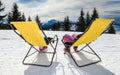 Two children on the lounge chairs on snow