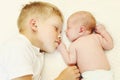 Two children lying on bed, eldest brother hugging youngest baby